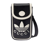 Black and white crossbody bag with Gucci and Adidas logos on a light gray background