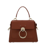 Brown handbag with gold ring detail on a white background