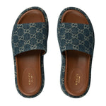 Pair of Gucci slides with blue patterned uppers and brown soles on a white background