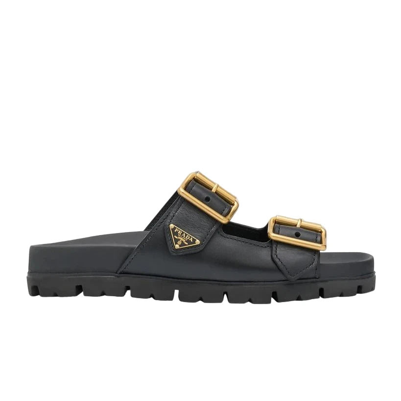 Black sandal with gold buckles on a light gray background