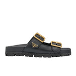 Black sandal with gold buckles on a light gray background