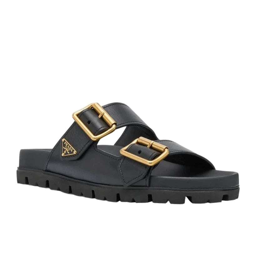 Black sandal with gold buckles on a light gray background