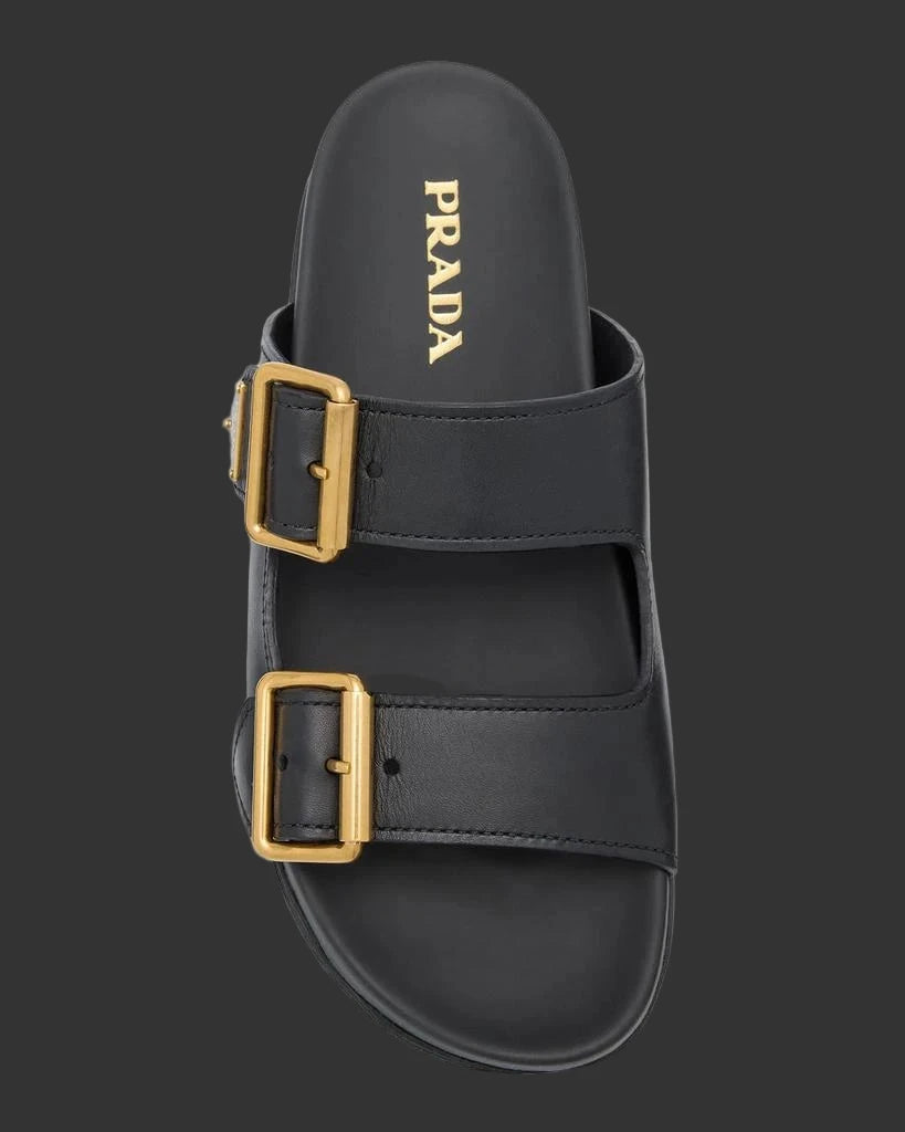 Black sandal with gold buckles and Prada logo on a light gray background
