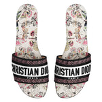 Pair of Christian Dior slides with butterfly pattern on a white background
