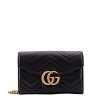 Black quilted handbag with gold chain and logo on a white background
