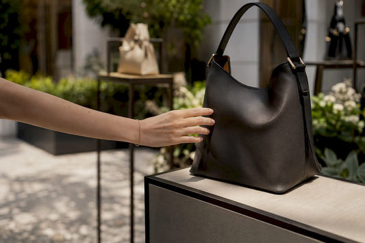 Customer reaching for handbag strap in luxury outlet