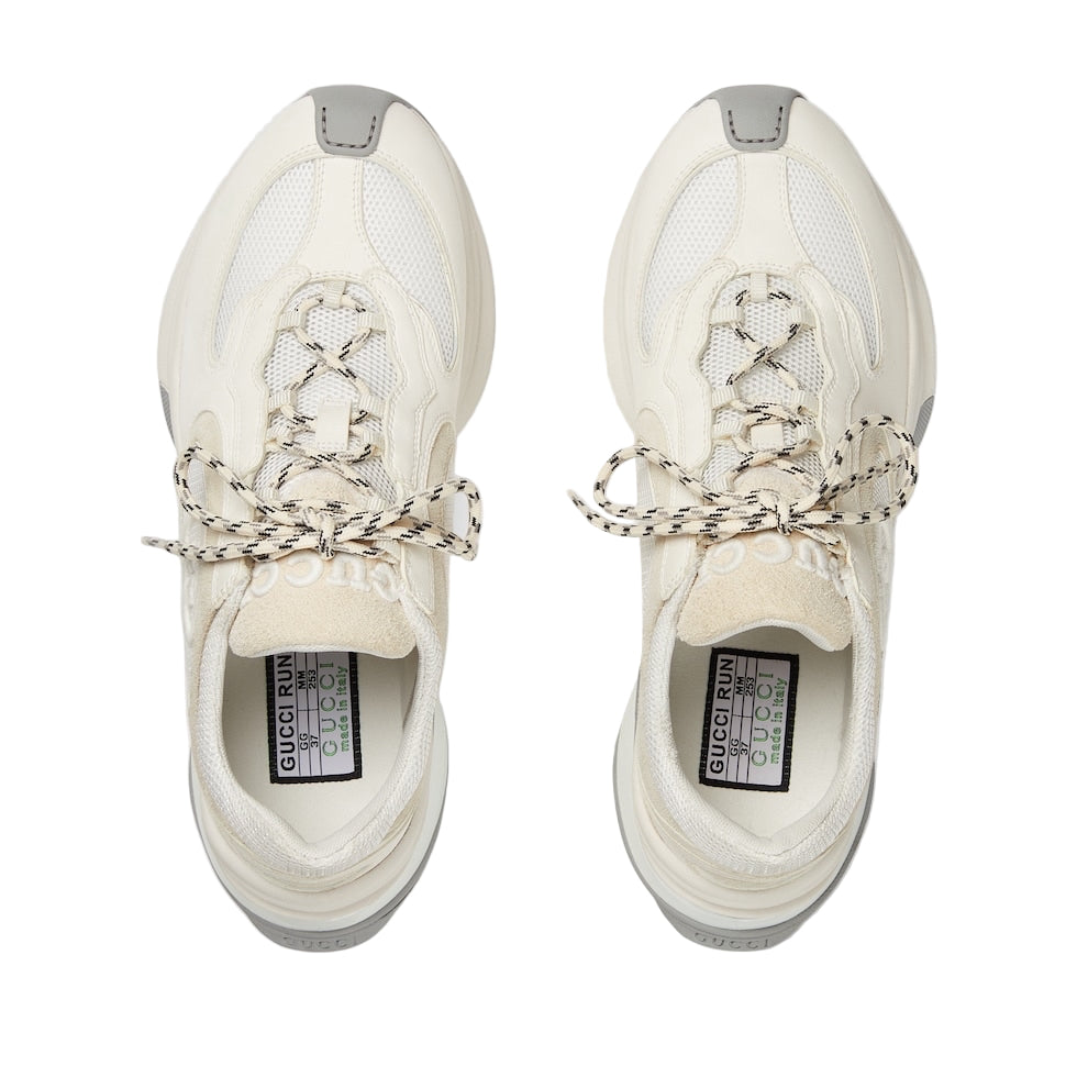 Pair of white sneakers with Gucci branding on a light gray background