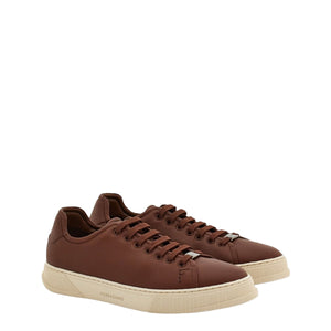 Brown sneakers with beige soles on a light gray background