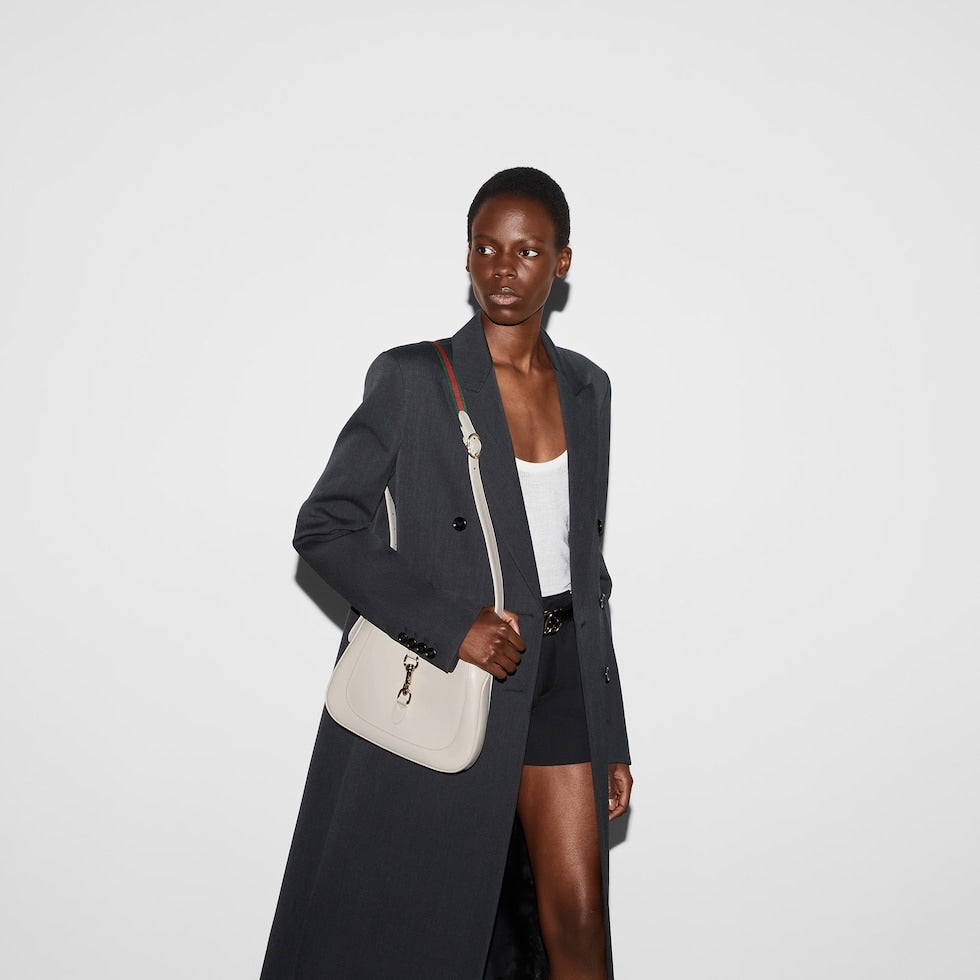 Woman holding a beige handbag against a white background