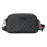 Black patterned Gucci bag with a strap on a light gray background
