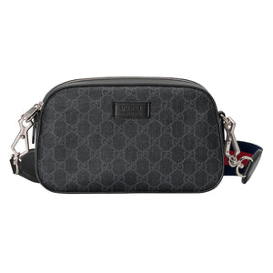 Black patterned Gucci bag with a strap on a light gray background