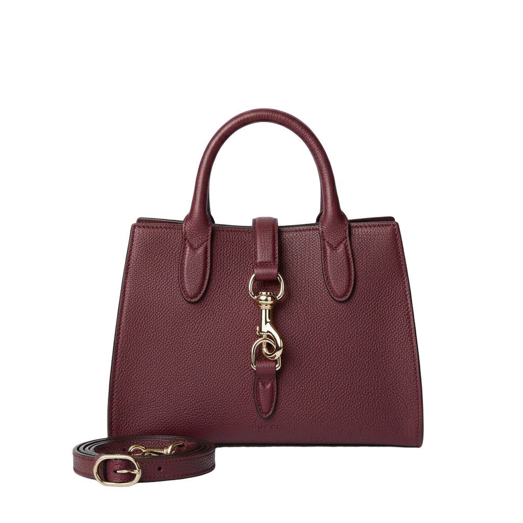 Burgundy handbag with gold clasp and matching belt on a light gray background