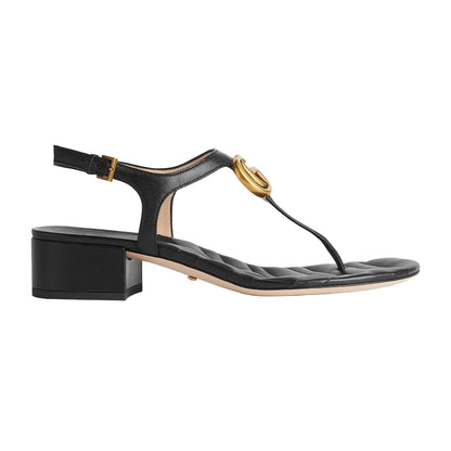 Black sandal with gold buckle on a light gray background