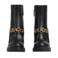 Black boots with gold 'Gucci' logo on a light gray background