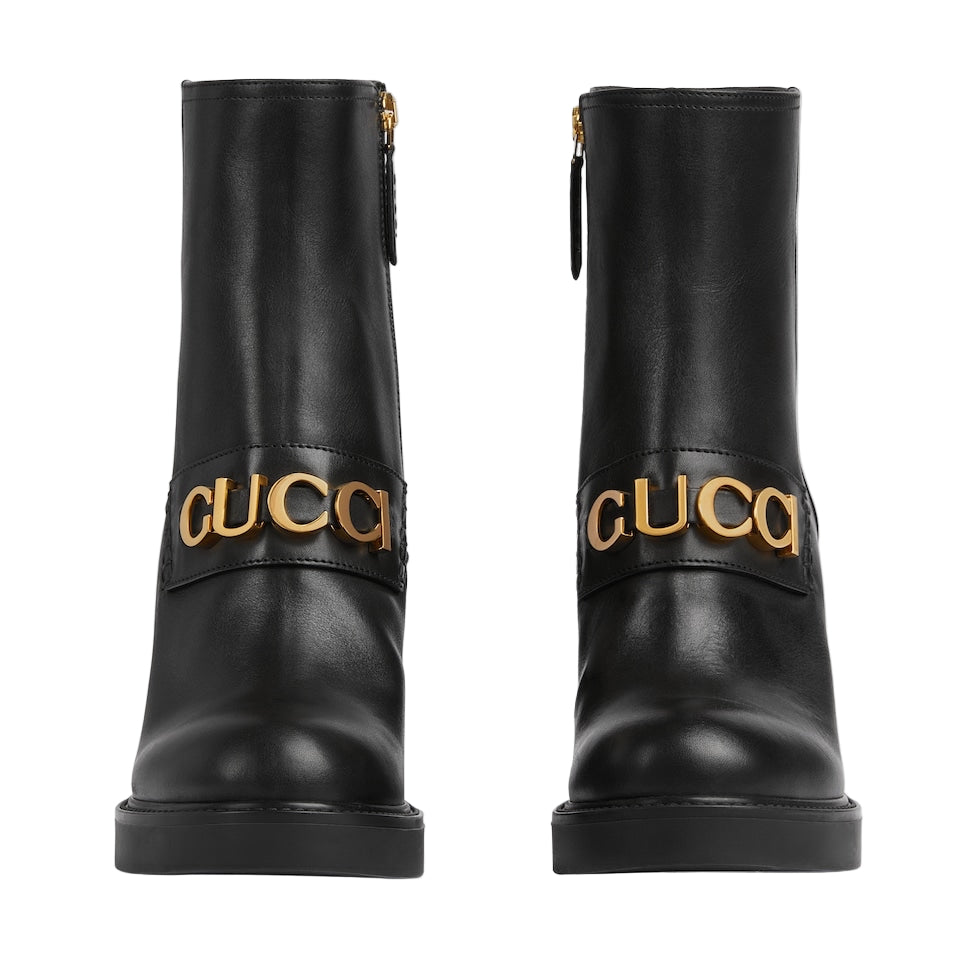 Black boots with gold 'Gucci' logo on a light gray background