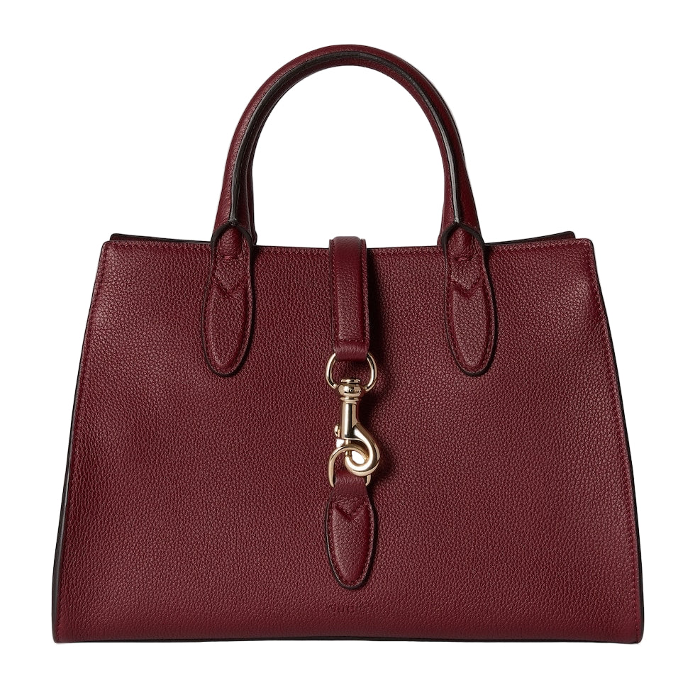 Burgundy handbag with a gold clasp on a light gray background