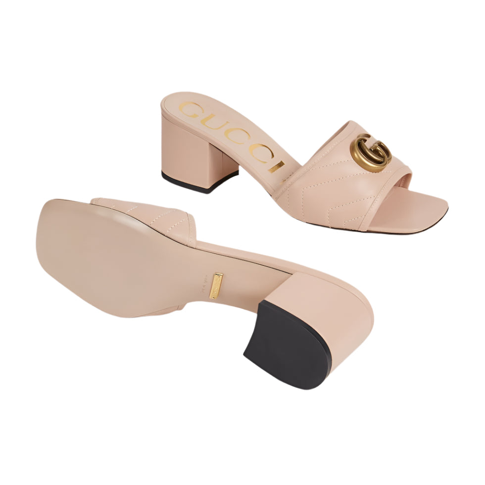 Pair of beige high-heeled sandals with Gucci logo on a light gray background