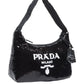 Black sequin handbag with Prada logo on a white background