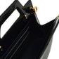 Close-up of a black handbag with gold accents on a white background