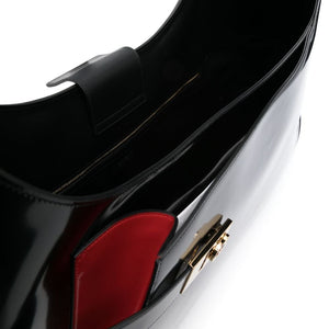 Close-up of a black and red handbag with a gold clasp on a white background