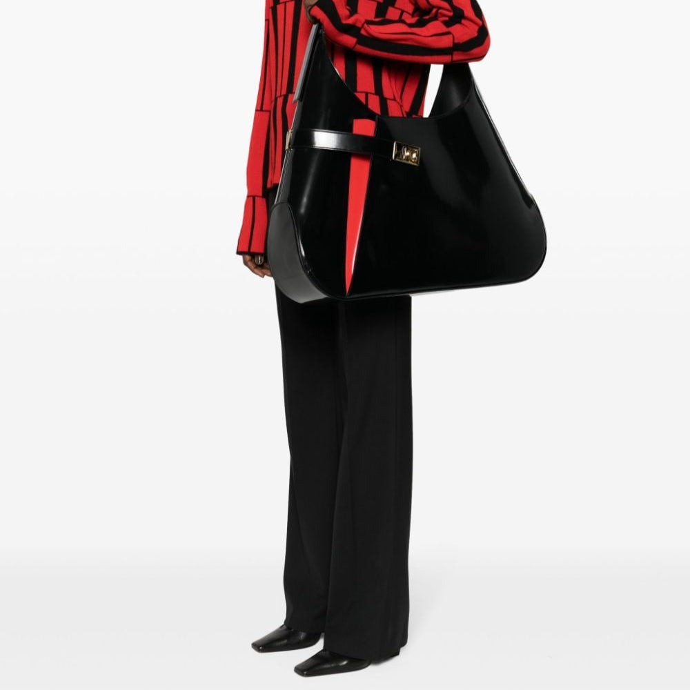 Person wearing a red and black striped shirt with a black handbag on a white background