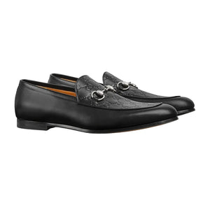 Pair of black leather loafers with decorative details on a white background