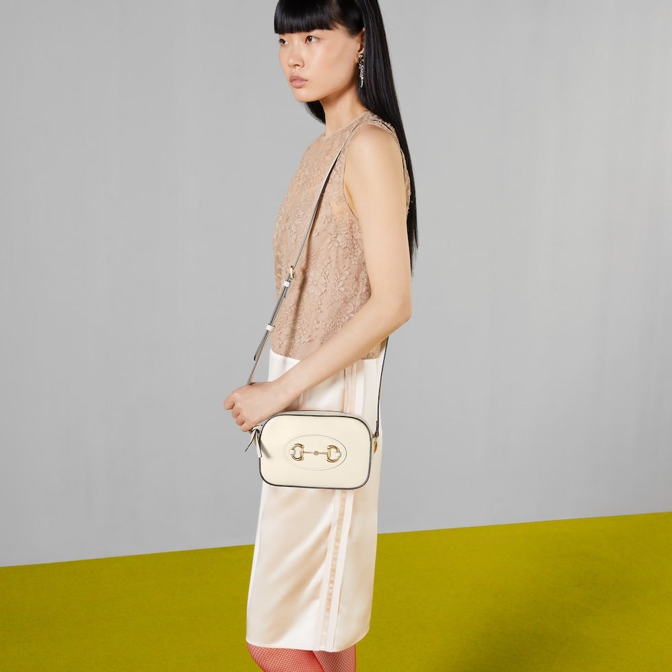 Woman holding a beige handbag against a gray and green background