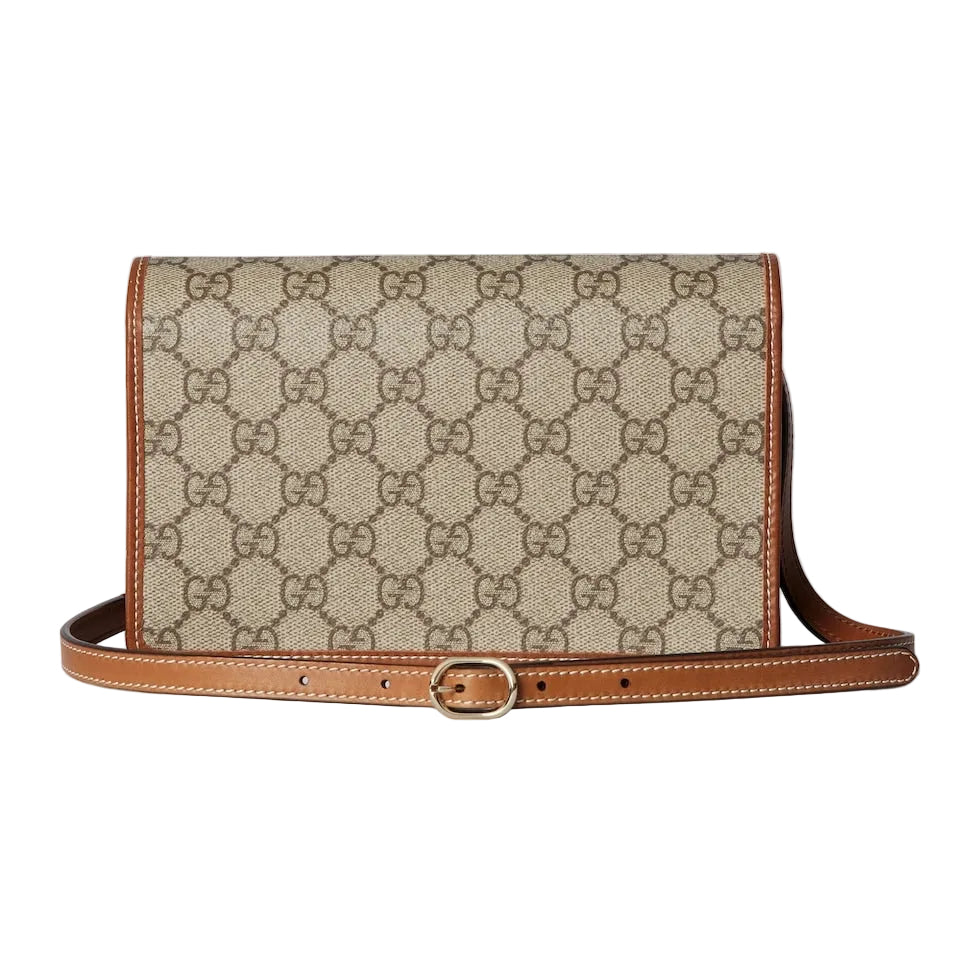 Beige handbag with brown leather strap on a light gray background