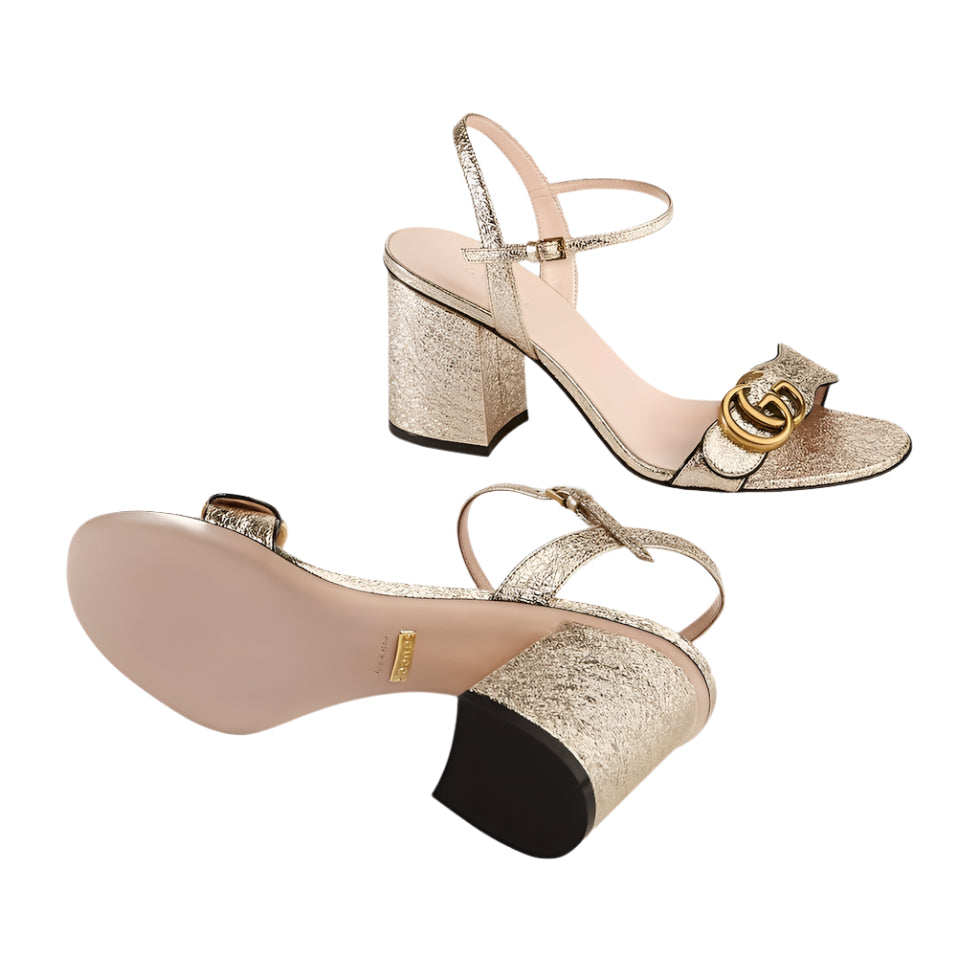 Gold glitter high-heeled sandals with a Gucci logo on a light gray background