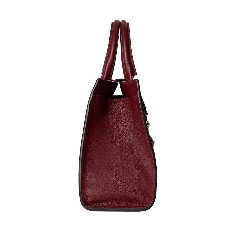 Red handbag with a textured surface on a light gray background