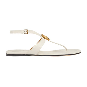 White sandal with a gold buckle on a light gray background