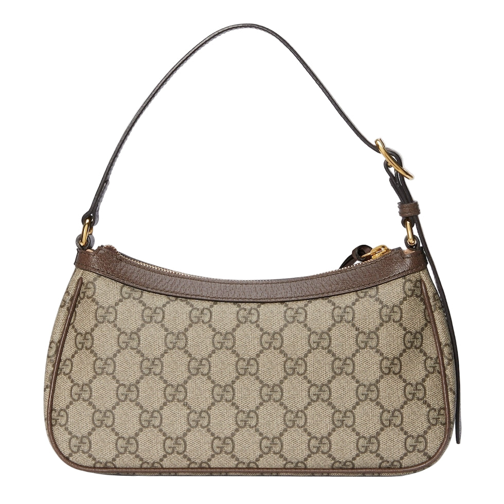 Designer handbag with patterned fabric and gold hardware on a light gray background