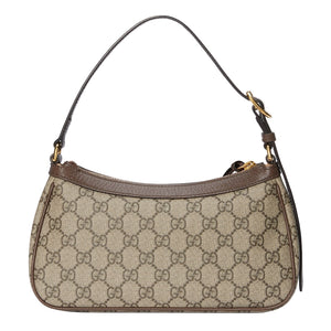 Designer handbag with patterned fabric and gold hardware on a light gray background