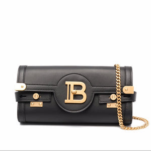 Black handbag with gold chain and logo on a white background