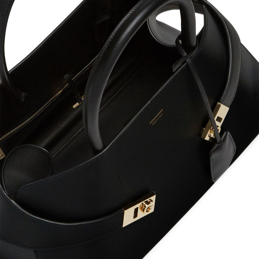 Black handbag with gold clasp on a white background