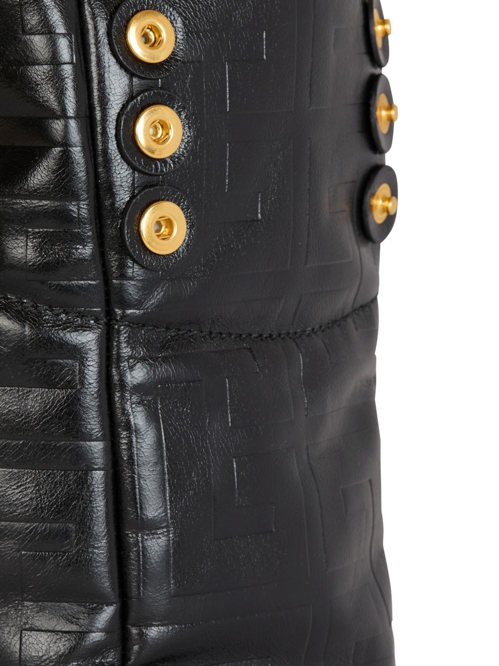 Close-up of a black leather jacket with gold buttons on a white background