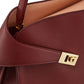 Close-up of a brown leather handbag with a gold clasp on a white background