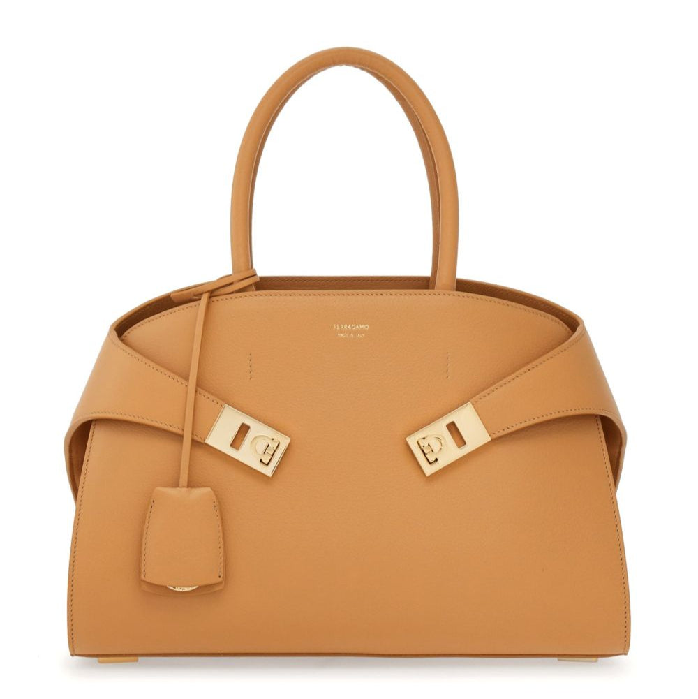 Tan handbag with gold hardware on a white background