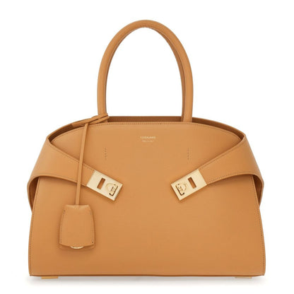 Tan handbag with gold hardware on a white background