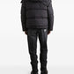 Person wearing a black puffer jacket and pants on a white background