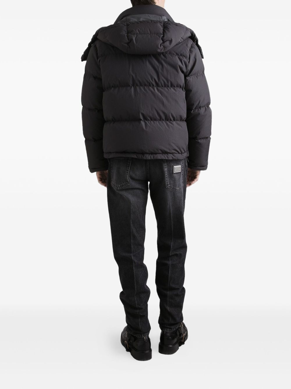 Person wearing a black puffer jacket and pants on a white background