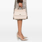 Person wearing a leopard print skirt and holding a beige handbag on a white background