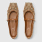 Pair of Gucci flats with decorative strap on a light gray background