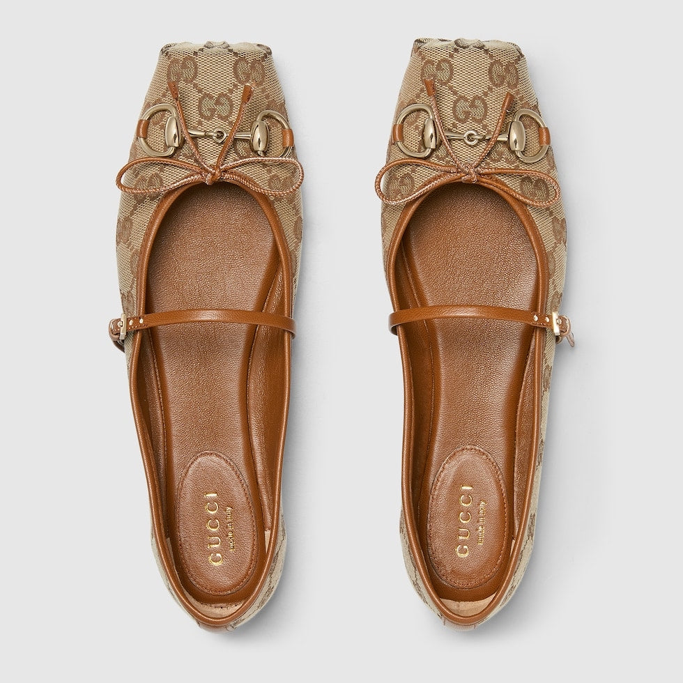Pair of Gucci flats with decorative strap on a light gray background