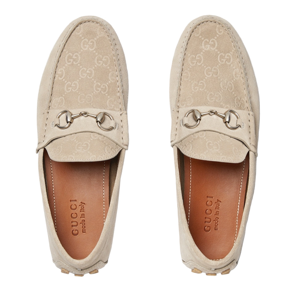 Pair of beige Gucci loafers on a light gray background