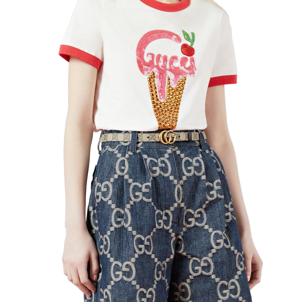 Person wearing a white t-shirt with a red ice cream cone design and blue jeans with a Gucci logo.
