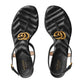 Black Gucci sandals with gold logo on a light gray background