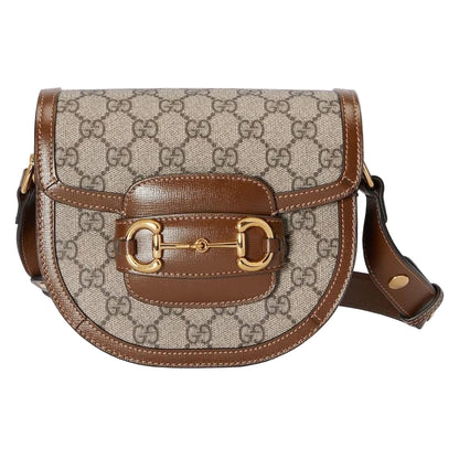 Designer handbag with patterned fabric and brown leather accents on a light gray background