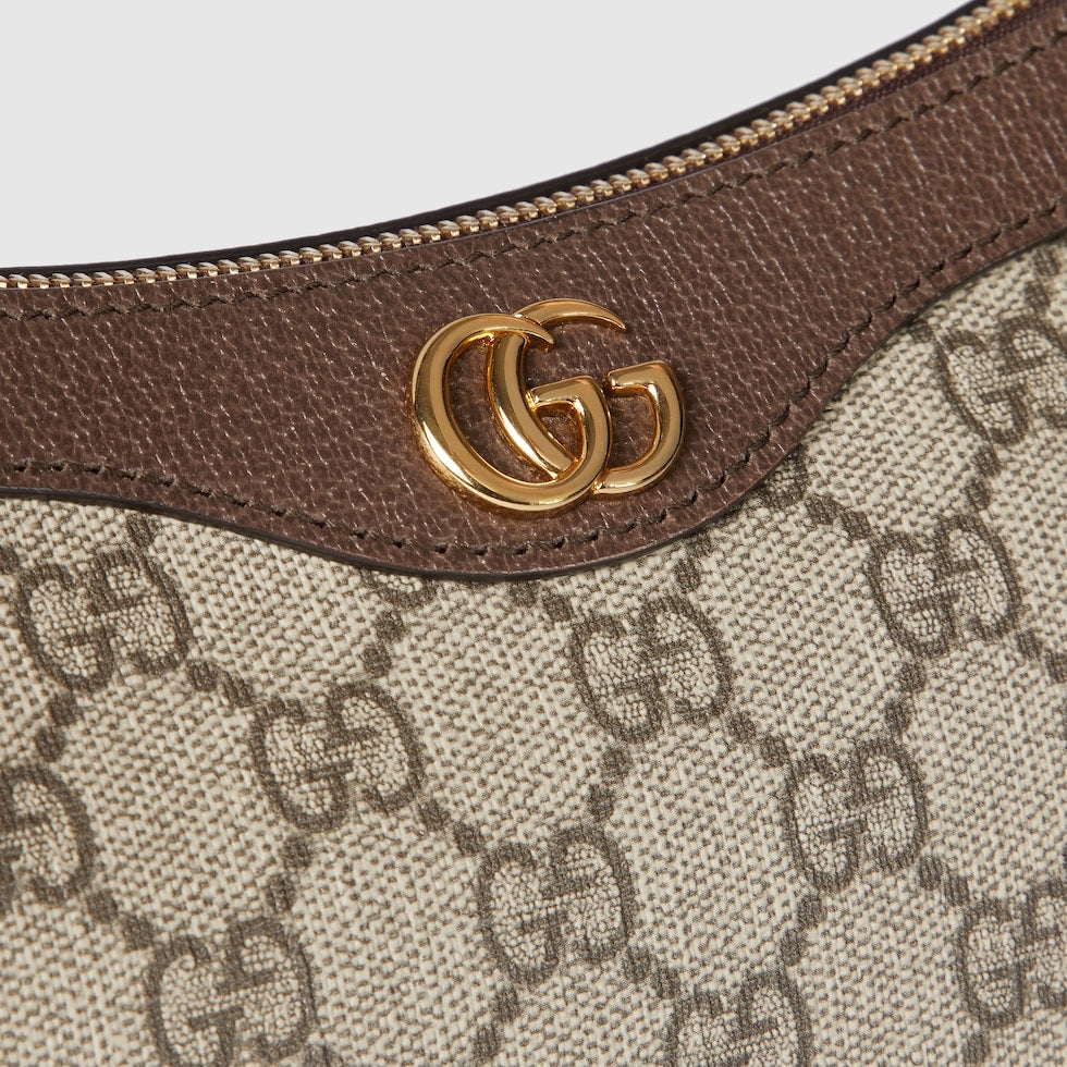 Close-up of a Gucci handbag with brown leather strap and gold logo.