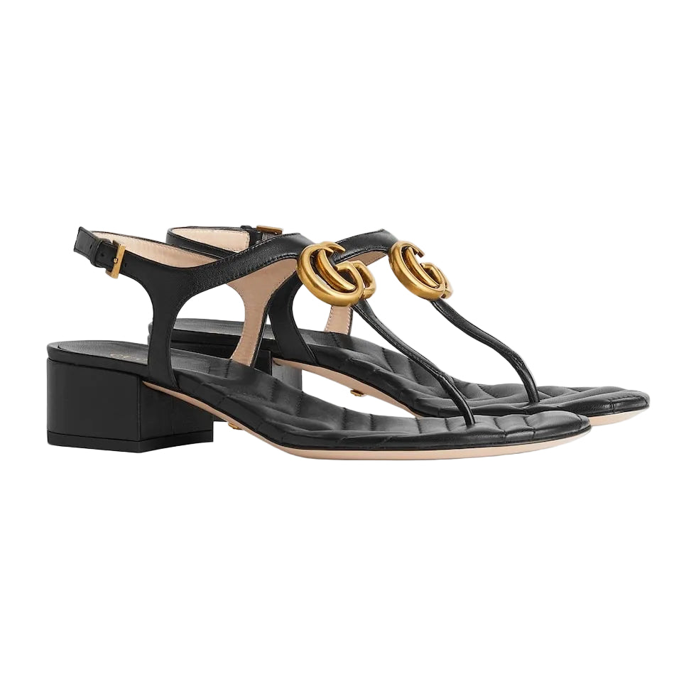 Black sandals with gold accents on a light gray background
